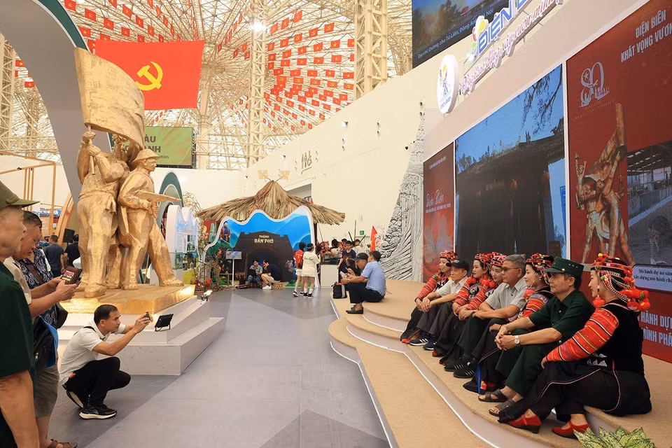 Visitantes se toman fotos de recuerdo con los pobladores de la etnia Ha Nhi en el área de exhibición de la provincia de Dien Bien. (Foto: VNA)