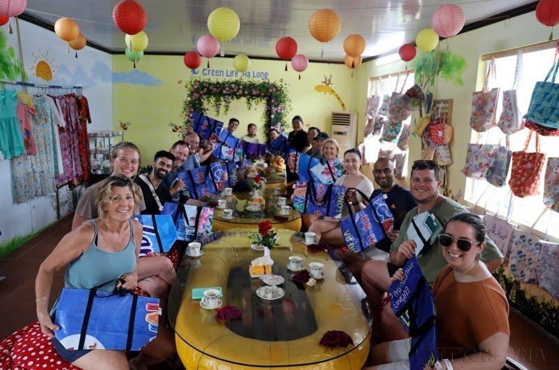 Turistas extranjeros muestran su entusiasmo por los bolsos hechos con lonas de plástico recicladas de la cooperativa Green Life Ha Long, en la provincia norteña de Quang Ninh. (Foto: VNA)