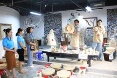 Turistas observan una exhibición de cerámica tradicional en la aldea artesanal de Bat Trang. (Fuente: hanoimoi.vn)