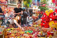 Las turistas extranjeras están interesadas ​​en conocer sobre los juguetes tradicionales vietnamitas del Festival del Medio Otoño. (Fuente: VNA)