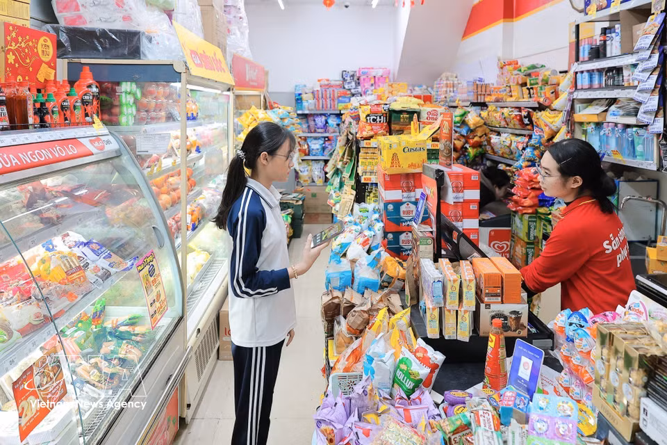 Las personas realizan pagos electrónicos en las compras, contribuyendo a fomentar el consumo sin efectivo. (Foto: VNA)