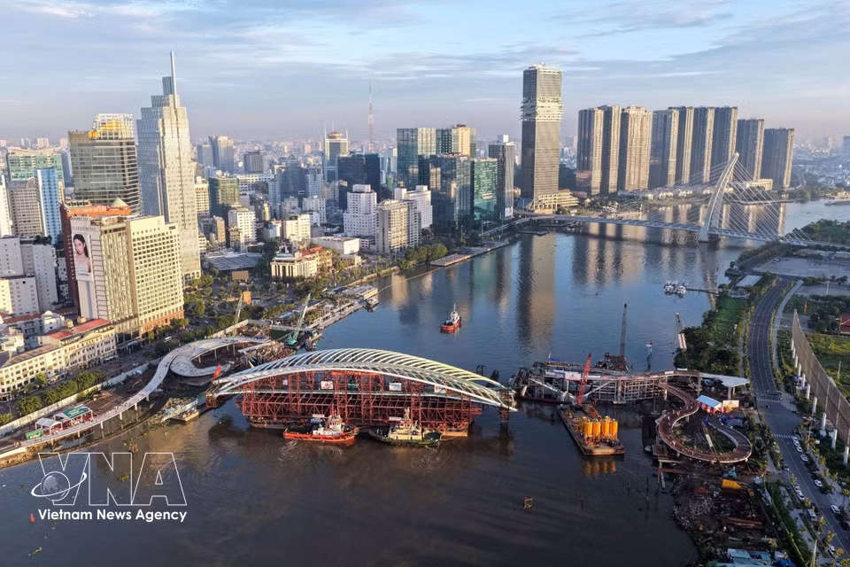 Una barcaza transporta el tramo principal hasta su posición para completar la unión de la estructura del puente peatonal sobre el río Saigón. Foto: VNA