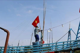 Pescadores izan la bandera de la Patria antes de zarpar para reafirmar la soberanía sobre las islas y mares de la Patria. (Foto: VNA)