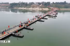 Personas y vehículos circulan con normalidad a través del puente flotante sobre el río Lo en la mañana del 16 de febrero. (Foto: VNA)