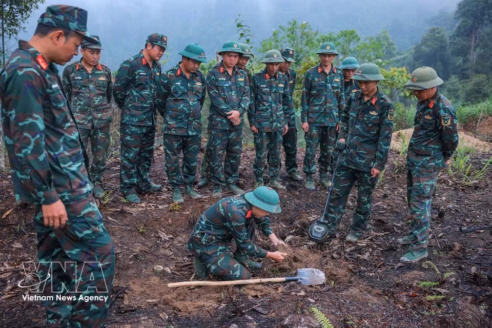 Los integrantes del equipo utilizan equipos de detección de minas para garantizar la seguridad del terreno antes de iniciar las labores de búsqueda. Foto: VNA