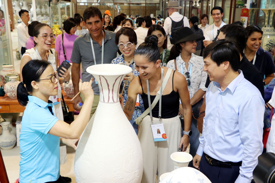 Los visitantes internacionales pintan motivos decorativos sobre jarrones de cerámica en proceso. (Foto: VNA)