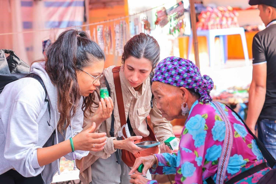 Turistas extranjeros exploran los productos disponibles en los mercados locales durante su visita a la meseta blanca de Bac Ha. Foto: VNA