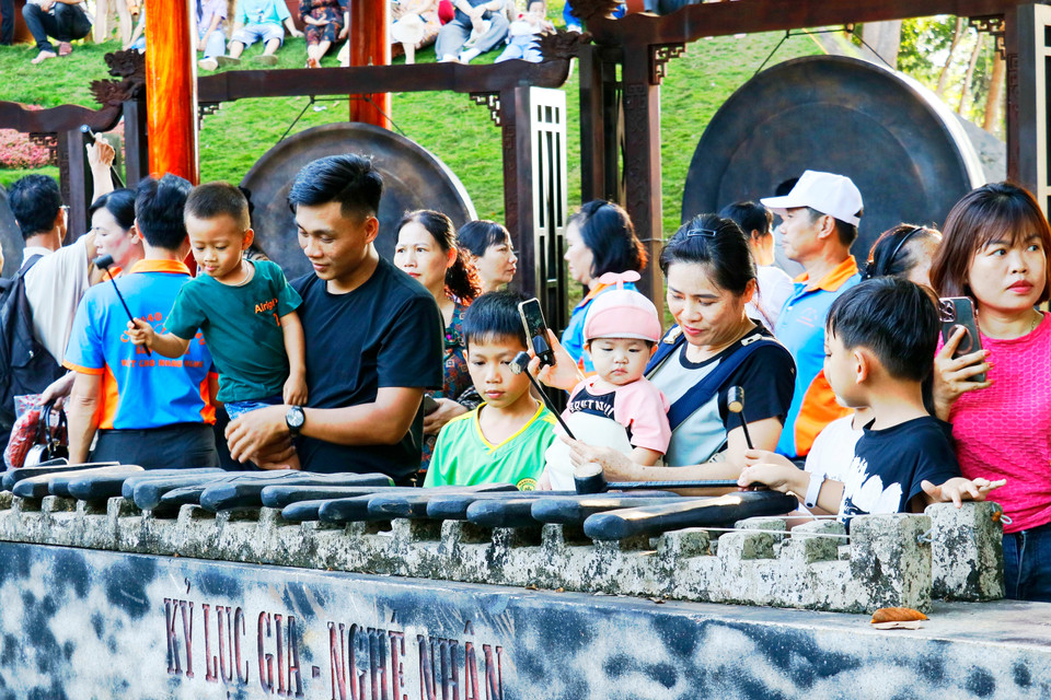 Visitantes se animan a tocar el xilófono de piedra como parte de una experiencia cultural interactiva en la aldea Bom Bo. Foto: VNA