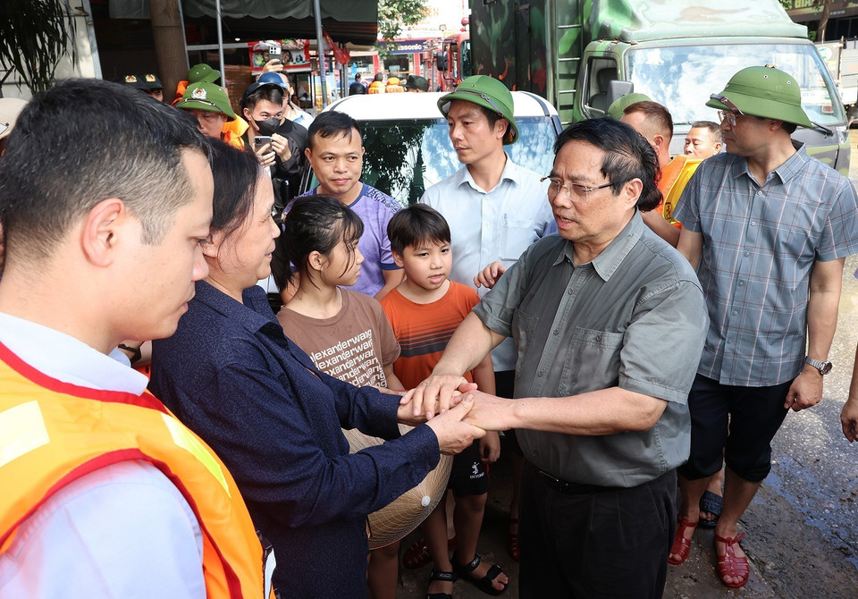 El primer ministro Pham Minh Chinh ofrece palabras de aliento y apoyo a la población afectada por las inundaciones en el barrio Phan Dinh Phung. (Foto: VNA)