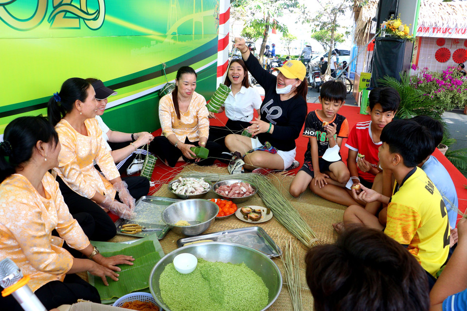 Turistas y pobladores locales comparten la experiencia de elaborar el “banh tet” o pastel cilíndrico de arroz glutinoso, una tradición culinaria del sur de Vietnam. (Foto: VNA)
