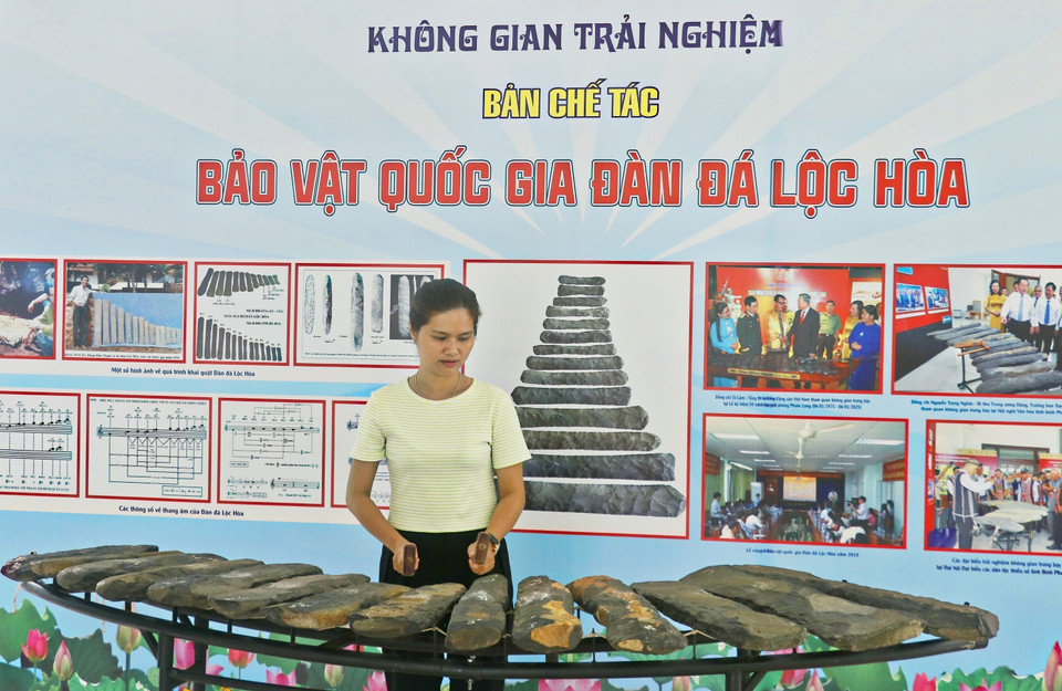 Turistas participan activamente tocando el xilófono de piedra en el Espacio Cultural de Binh Phuoc. Foto: VNA