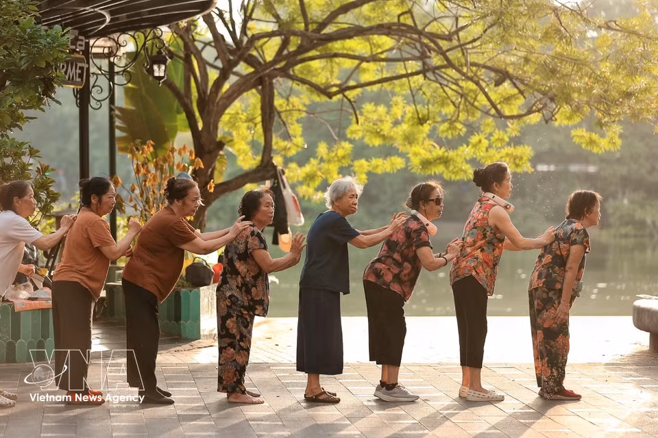 Un grupo de mujeres mayores realiza conjuntamente ejercicios físicos, creando un ambiente alegre y fortaleciendo los vínculos en las actividades comunitarias. Foto: VNA