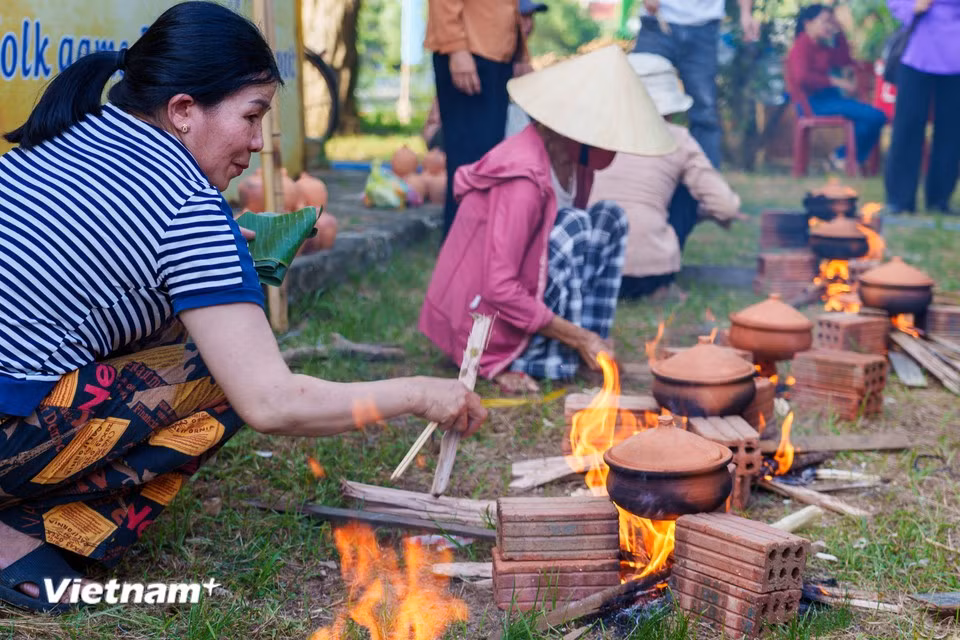 Los participantes ajustan hábilmente la llama para garantizar que el arroz de la olla de barro se cocine de manera uniforme y conserve su sabor. (Foto: Vietnam+)