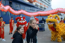 Los turistas del Celebrity Solstice disfrutan tomándose fotos con un equipo de danza del león y el dragón. (Fuente: VNA)