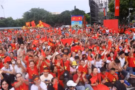 Numerosas personas con banderas rojas y estrellas amarillas en la intersección de Hung Vuong y Tran Phu esperan para presenciar el ensayo. (Fuente: VNA)