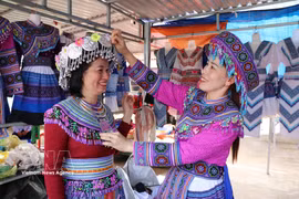 Turistas experimentan el uso de trajes tradicionales de la etnia H’Mong en el mercado de Dak R’mang. (Fuente: VNA)