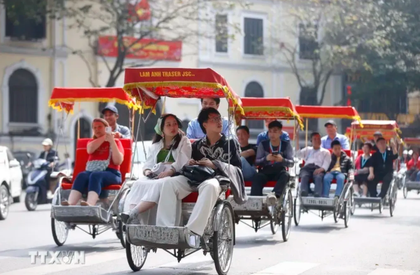 Turistas extranjeros experimentan un recorrido en triciclo alrededor del lago Hoan Kiem en Hanoi (Foto: VMA)