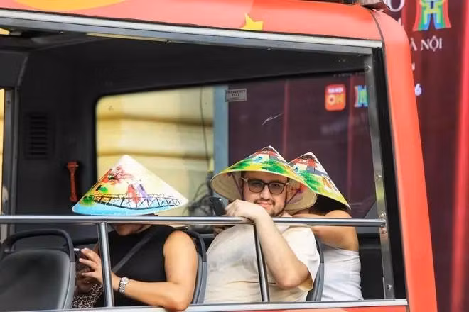 Du_khách_nước_ngoài_trải_nghiệm_tham_quan_phố_cổ_Hà_Nội_trên_xe_điện.(TTXVN).webp