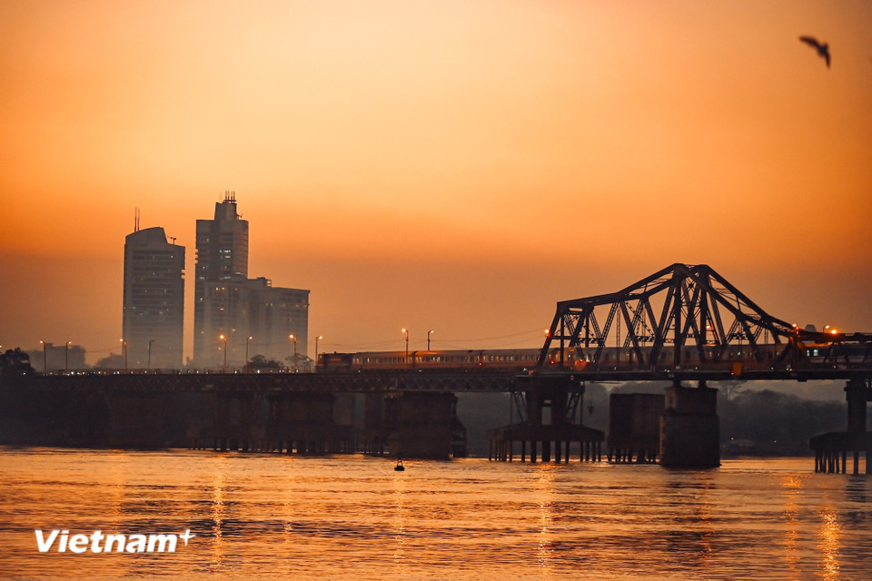 Podemos detenernos a admirar desde la distancia el puente Long Bien, donde el atardecer tiñe de rojo la superficie del agua, observando silenciosamente cómo el tren avanza lentamente hacia el centro de la ciudad. (Foto: Vietnam+)