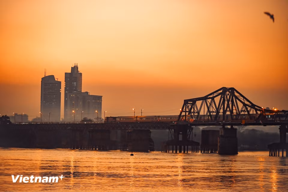 Podemos detenernos a admirar desde la distancia el puente Long Bien, donde el atardecer tiñe de rojo la superficie del agua, observando silenciosamente cómo el tren avanza lentamente hacia el centro de la ciudad. (Foto: Vietnam+)