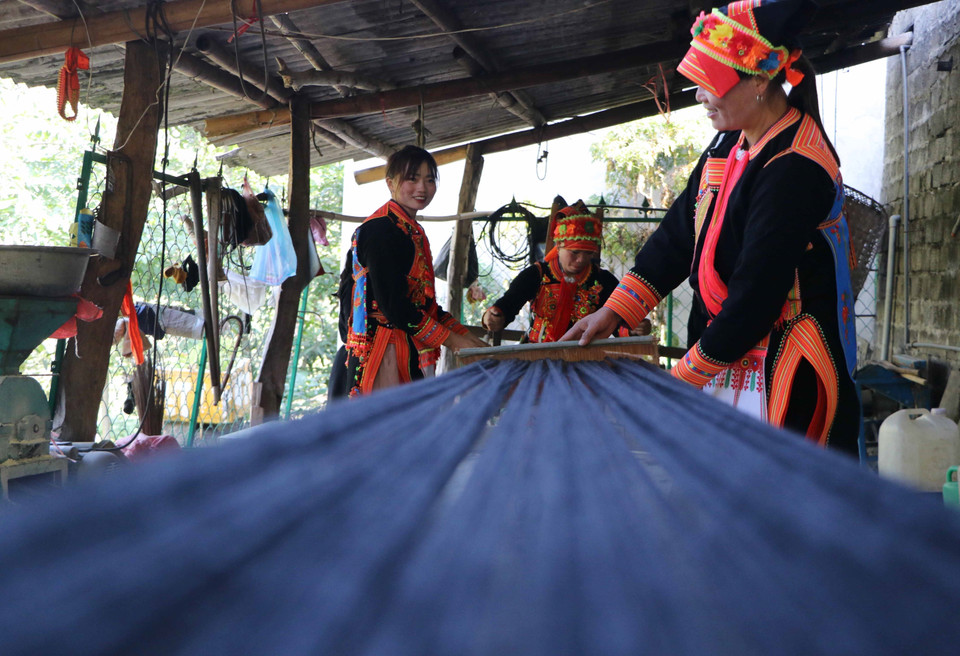 Brillantes hilos negros que forman el característico traje de las mujeres Dao. Foto: VNA