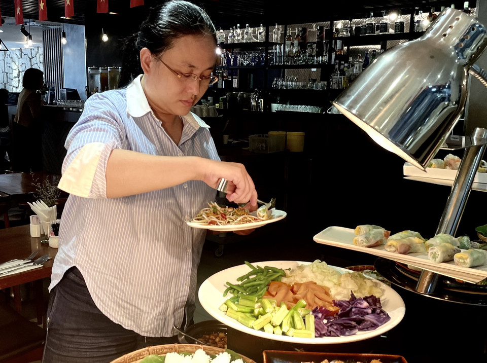 Los comensales disfrutan de varios platos de Nom rau (ensalada de verduras). Foto: VNA