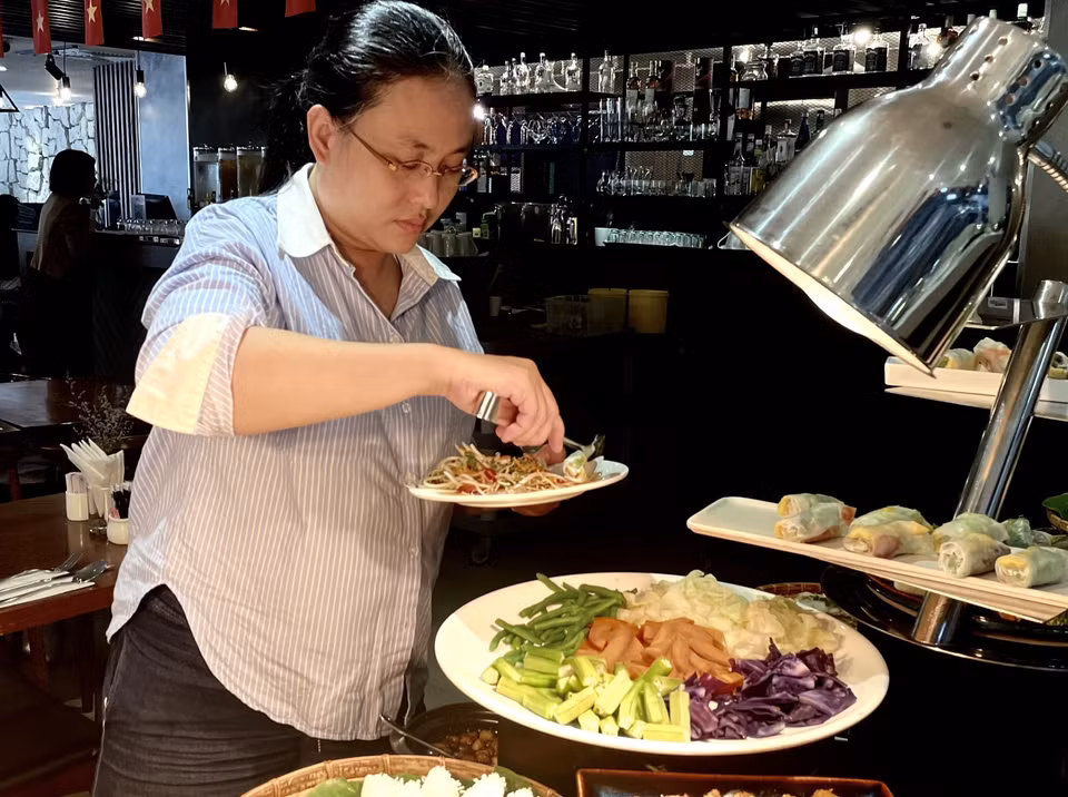 Los comensales disfrutan de varios platos de Nom rau (ensalada de verduras). Foto: VNA