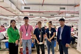 Le Ngoc Toan, primer secretario y jefe de la Junta Directiva de trabajadores y expertos en Malasia (primero a la derecha) y trabajadores vietnamitas en la empresa Ramatex Textiles. (Fuente: VNA)