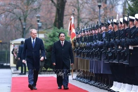 El primer ministro de Polonia, Donald Tusk, y su homólogo vietnamita, Pham Minh Chinh, pasan revista a la guardia de honor. (Fuente: VNA)