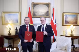 El secretario general del Partido Comunista de Vietnam, To Lam, y el primer ministro de Reino Unido, Keir Starmer, entregan la Declaración conjunta sobre la elevación de los nexos bilaterales a una asociación estratégica integral. (Foto: VNA)