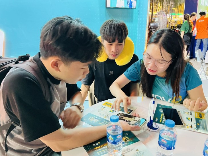 La personal guía a visitantes que utilicen la aplicación bancaria al pagar. (Foto: VNA)