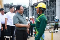 El primer ministro Pham Minh Chinh con los trabajadores que construyen el proyecto del Aeropuerto Internacional de Phu Quoc. (Foto: VNA)