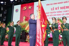 El secretario general del Partido Comunista de Vietnam, To Lam, coloca el título de Héroe de las Fuerzas Armadas Populares en la Bandera de la Victoria del Departamento General de Industria de Defensa. (Foto: VNA)