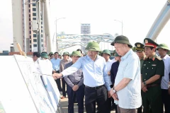 El secretario general del Partido Comunista de Vietnam, To Lam, escucha el informe del líder de la provincia de Thai Nguyen sobre las labores para superar las consecuencias de la tormenta y las inundaciones en el puente Ben Tuong. (Foto: VNA)