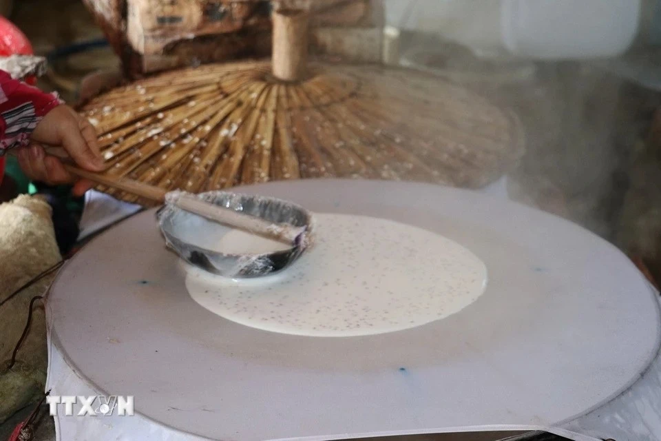 El paso de recubrimiento de la mezcla hecha de harina de arroz, sésamo y leche de coco debe realizarse de manera rápida y uniforme para garantizar que el panqueque tenga el grosor adecuado. (Foto: VNA)