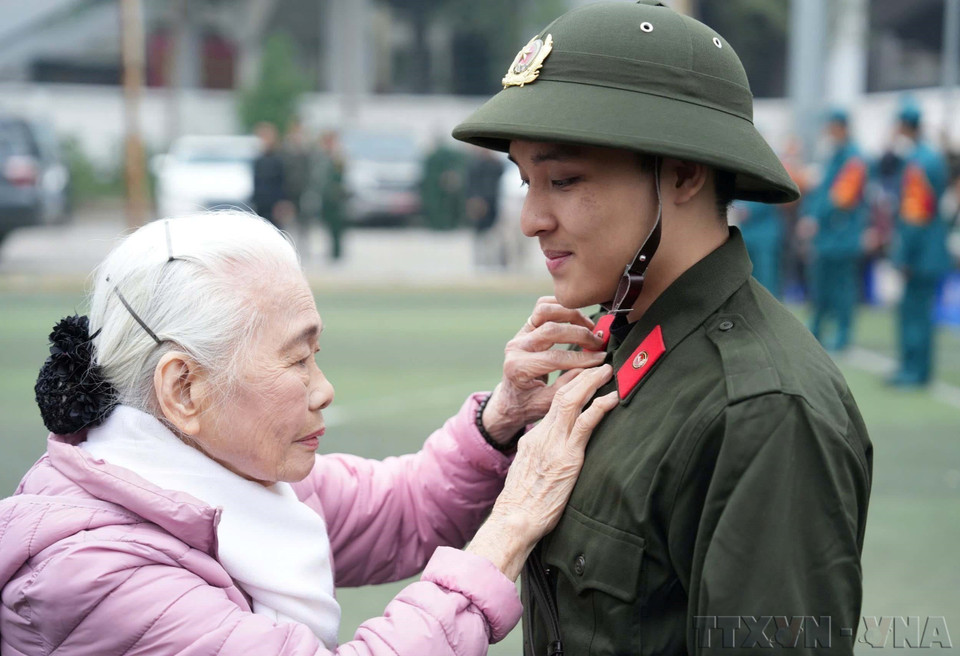 La señora Nguyen Thi Minh Thuan, de 90 años de edad, despide a su nieto cuando se va a cumplir con su deber de seguridad pública en el distrito de Dong Da, Hanoi (febrero de 2025). (Fuente: VNA)