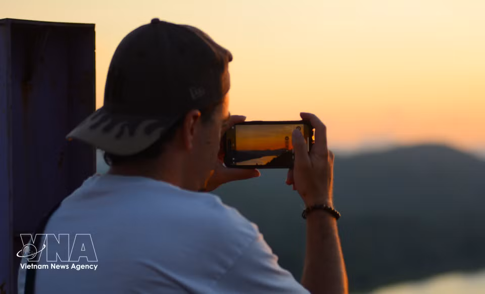 Turistas extranjeros toman fotos del paisaje alrededor de la colina al atardecer. (Fuente: VNA)