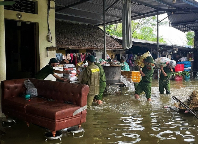 La policía y las fuerzas de seguridad ayudan a los pobladores en una zona inundada trasladar sus pertenencias. (Foto: VNA) vna-potal-cong-an-tinh-bac-ninh-ung-truc-xuyen-dem-bao-dam-an-toan-cho-nguoi-dan-trong-mua-lu-8321939.jpg