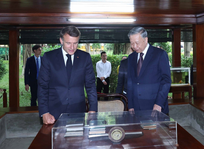 Los dos dirigentes visitan la casa sobre pilotes del Presidente Ho Chi Minh en su Área de Reliquias (Foto: VNA) vna-potal-tong-bi-thu-to-lam-va-tong-thong-phap-tham-khu-di-tich-chu-tich-ho-chi-minh-tai-phu-chu-tich-8055578.jpg