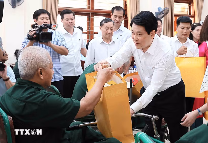 El presidente Luong Cuong entrega obsequios a Nguyen Xuan Mai, inválido de guerra, quien recibe tratamiento en el Centro de Rehabilitación de Veteranos de Guerra de Duy Tien. (Foto: VNA)