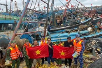 Guardias fronterizos de Hai Phong entregan banderas nacionales a pescadores en el puerto de Bach Long Vy. (Foto: VNA)