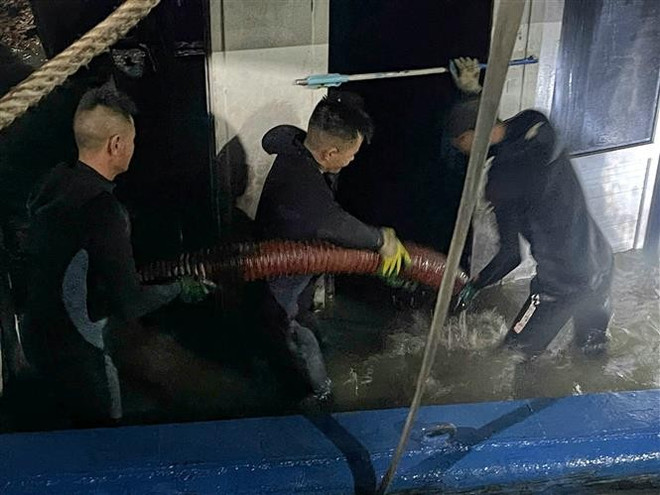 Las fuerzas bombean agua del barco antes de remolcarlo. (Foto: VNA) vna-potal-vu-lat-tau-tren-vinh-ha-long-truc-vot-thanh-cong-va-lai-dat-tau-ve-bo-8159125.jpg