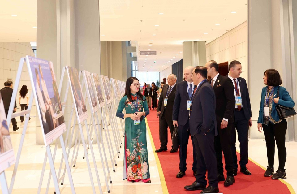 Delegados internacionales recorren la exposición fotográfica de la VNA durante la ceremonia de firma de la Convención de Hanoi, en la mañana del 25 de octubre. (Foto: VNA)