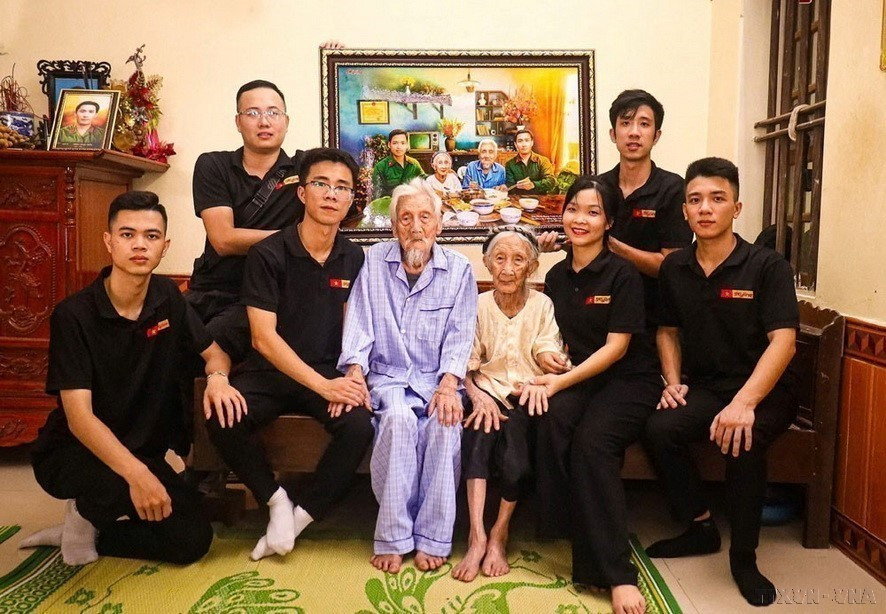 El grupo de restauración de imágenes Skyline entrega a la Madre Heroína de Vietnam Nguyen Thi Ngach una fotografía que simula una comida familiar con sus dos hijos. (Fuente: VNA)