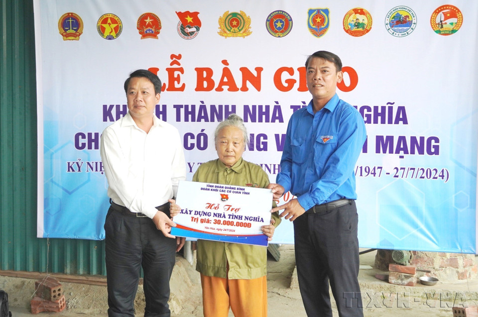 Líderes de los comités partidistas y de las uniones de Jóvenes Comunistas Ho Chi Minh de diferentes organismos de la provincia de Quang Binh entregan un cartel de apoyo financiero para la construcción de una casa a la familia de Le Thi Nhung (nacida en 1947), quien participó en la resistencia contra los estadounidenses para salvar al país. (Fuente: VNA)