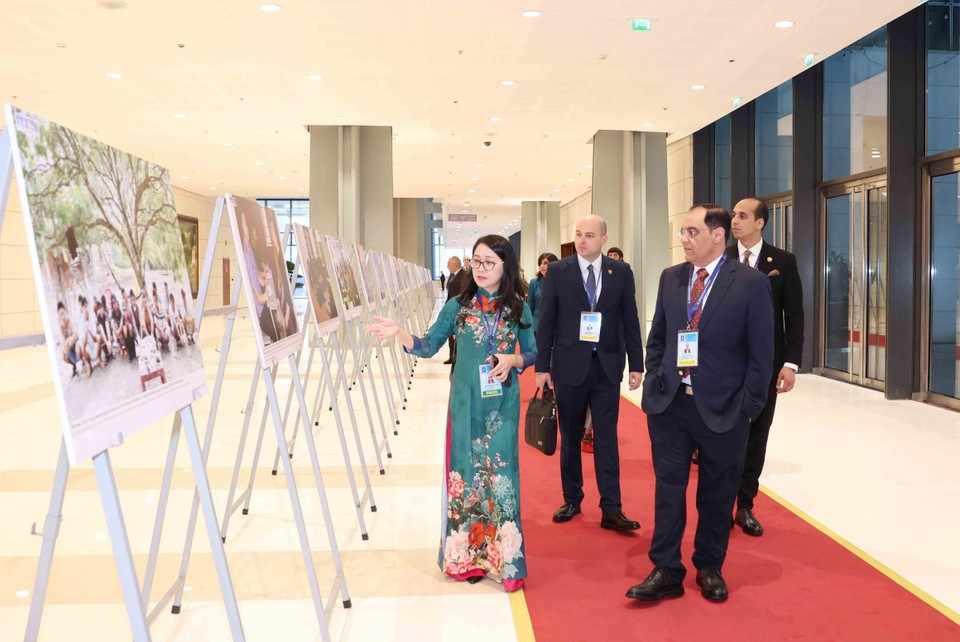 Delegados internacionales recorren la exposición fotográfica de la VNA durante la ceremonia de firma de la Convención de Hanoi, en la mañana del 25 de octubre. (Foto: VNA)