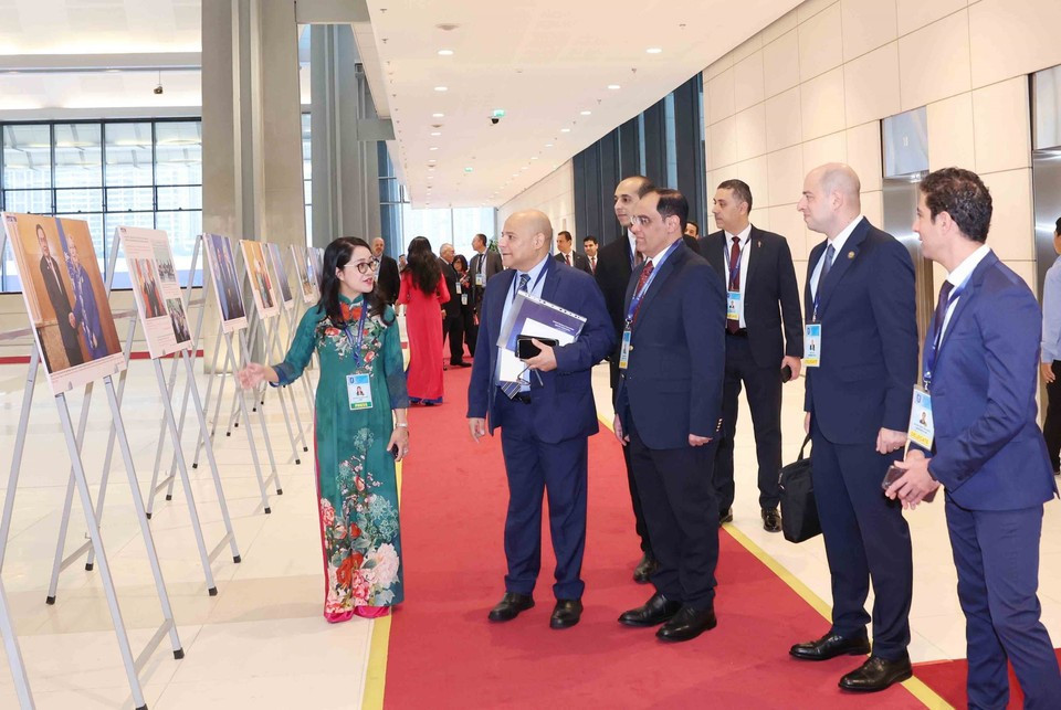 Delegados internacionales recorren la exposición fotográfica de la VNA durante la ceremonia de firma de la Convención de Hanoi, en la mañana del 25 de octubre. (Foto: VNA)