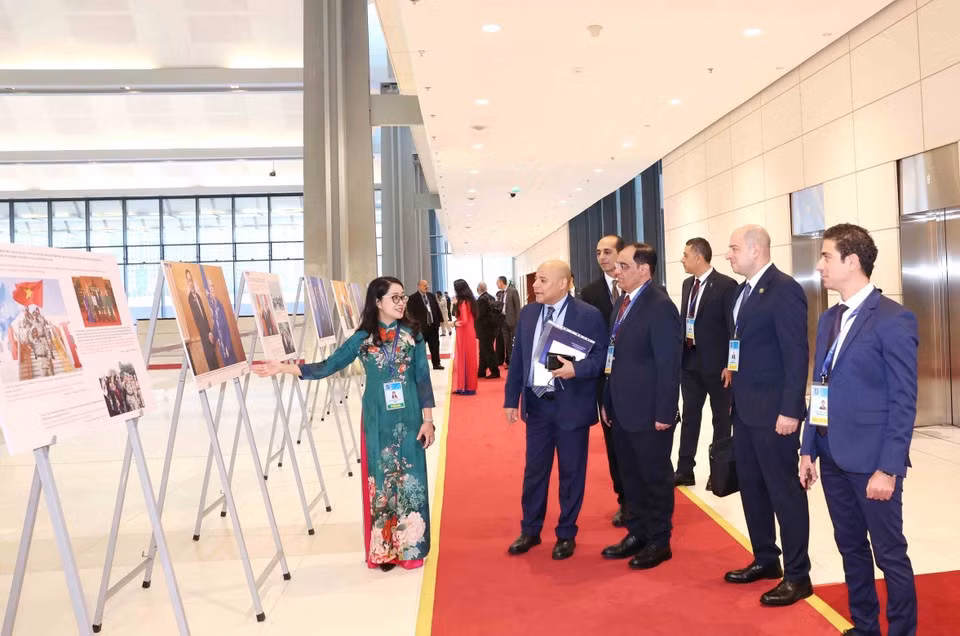 Delegados internacionales recorren la exposición fotográfica de la VNA durante la ceremonia de firma de la Convención de Hanoi, en la mañana del 25 de octubre. (Foto: VNA)