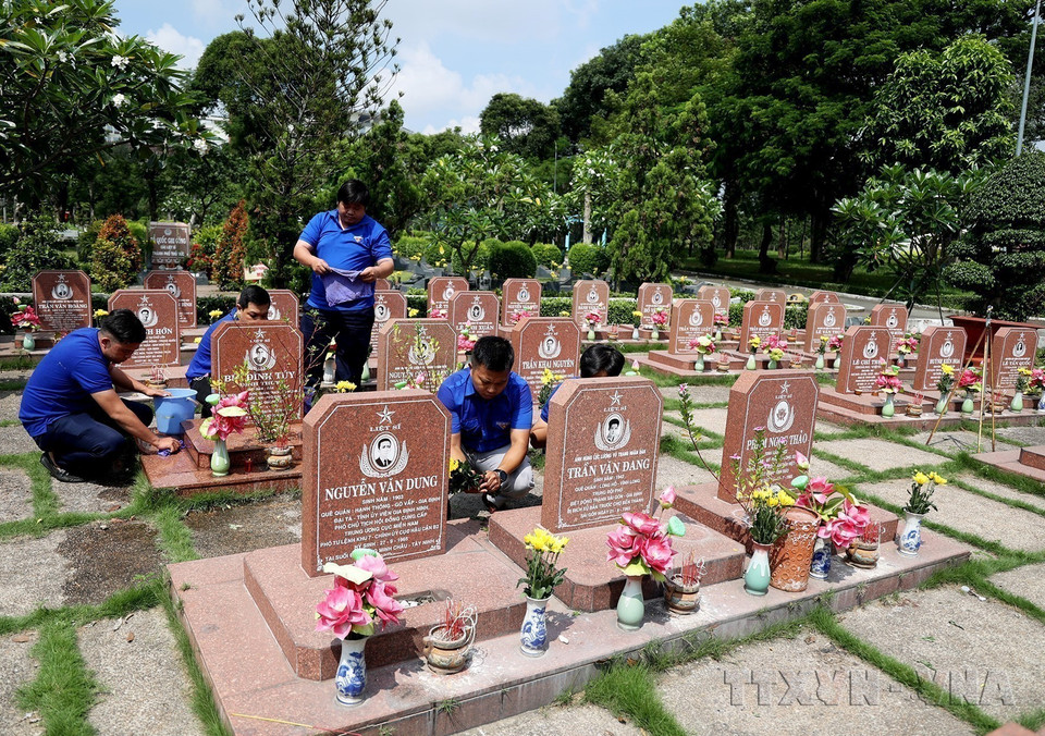 Miembros de la filial de la Unión de Jóvenes Comunistas Ho Chi Minh del barrio de Long Binh, ciudad de Thu Duc, cuidan las tumbas de comabtientes en el Cementerio de los Mártires de Ciudad Ho Chi Minh. (Fuente: VNA)