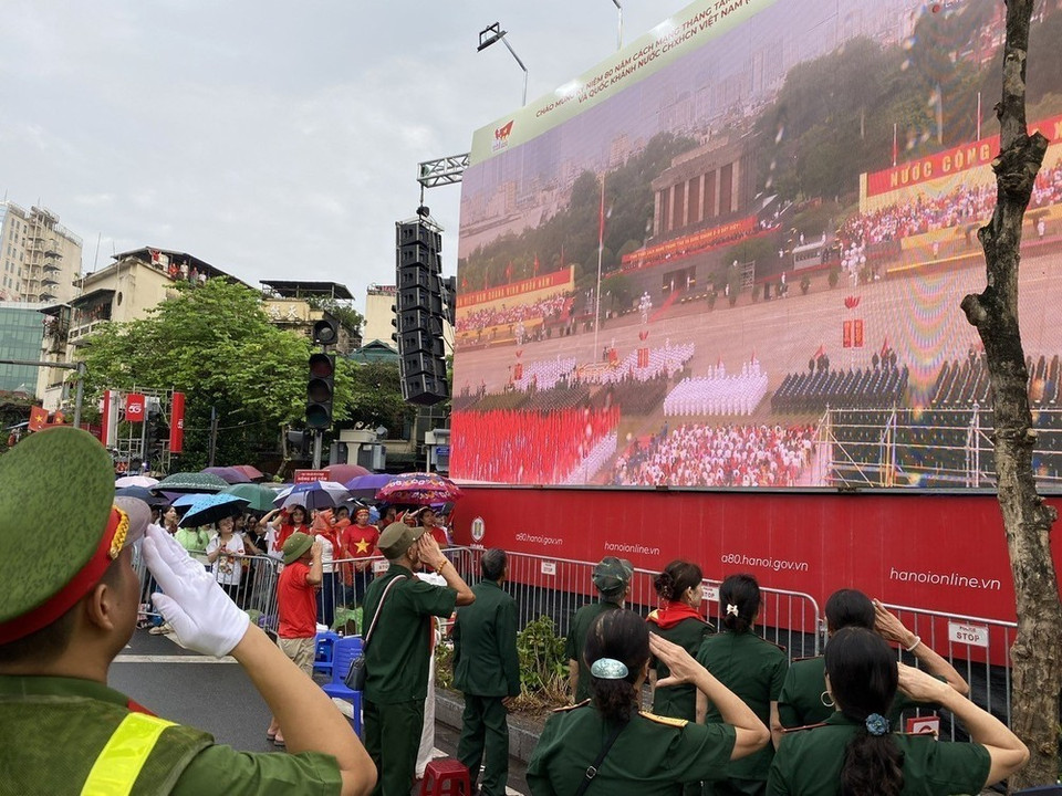 La gente en el área de Cua Nam realiza la ceremonia de izado de la bandera a través de una transmisión en vivo. (Foto: Vu Sinh - VNA)
